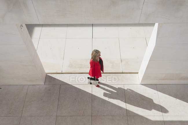 Вид зверху на жінку в червоному пальто, що йде по місту — стокове фото