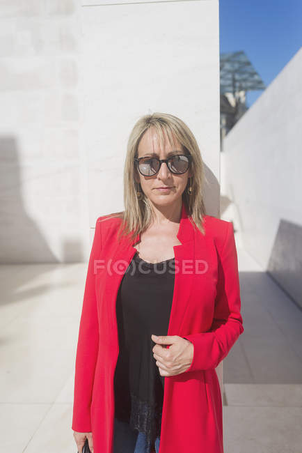 Жінка в сонцезахисних окулярах дивиться на камеру на міській міській вулиці — стокове фото