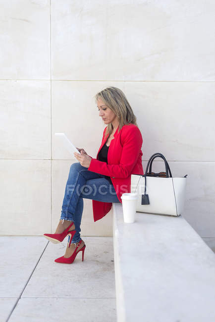 Жінка сидить на сходах і використовує цифровий планшет на відкритому повітрі — стокове фото