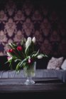 Glass vase with tulips in home interior — Stock Photo