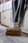 Vintage metal mug with spoon on pile of antique books — Stock Photo