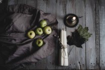 Natureza morta de maçãs, velas e folhas na mesa de madeira — Fotografia de Stock