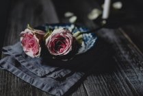 Рожеві троянди в старовинній керамічній мисці на сільському столі — стокове фото