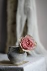 Рожева троянда в старовинній керамічній вазі на столі, крупним планом — стокове фото