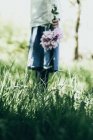 Vista cortada de menina segurando monte de flores no jardim — Fotografia de Stock