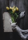 Bando de tulipas amarelas envoltas em tule na mesa rústica — Fotografia de Stock