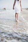 Обрезанный вид босиком женщины, идущей по пляжу — стоковое фото