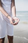 Обрезанный вид девушки-подростка, держащей камешки в руках на пляже — стоковое фото