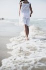 Vista cortada de mulher descalça andando na praia — Fotografia de Stock