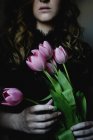 Abgeschnittene Ansicht einer jungen Frau mit einem Strauß rosa Tulpen. — Stockfoto