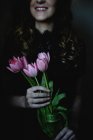 Vista recortada de una mujer joven sosteniendo un ramo de tulipanes rosados . - foto de stock