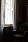 Интерьер комнаты с креслом и цветами на подоконнике — стоковое фото
