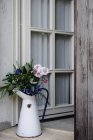 Arrangement floral avec des bleuets colorés dans une cruche en métal sur le porche — Photo de stock