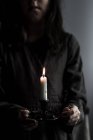 Cropped view of girl holding candle in candlestick. — Stock Photo