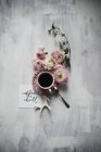 Cup of coffee on table with persian buttercup flowers — Stock Photo