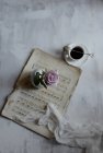 Pink rose on table with cup of coffee and sheet music — Stock Photo