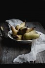 Still life with pears in porcelain bowl on rustic table — Stock Photo