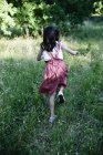 Rear view of girl running on grass in countryside garden. — Stock Photo