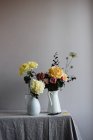 Bouquets florais amarelos em vasos cerâmicos na mesa — Fotografia de Stock