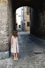 Girl in grey dress standing in passage in old town. — Stock Photo