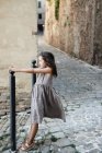 Girl playing and holding guard stone on street in old town. — Stock Photo