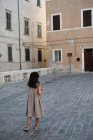 Mädchen in grauem Kleid spaziert durch die Altstadt. — Stockfoto