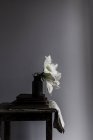 Квіти білої лілії у вазі на книжковій купі на сільському столі — стокове фото