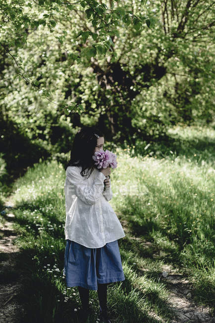 Дівчина тримає купу рожевих півоній в сільському саду . — стокове фото