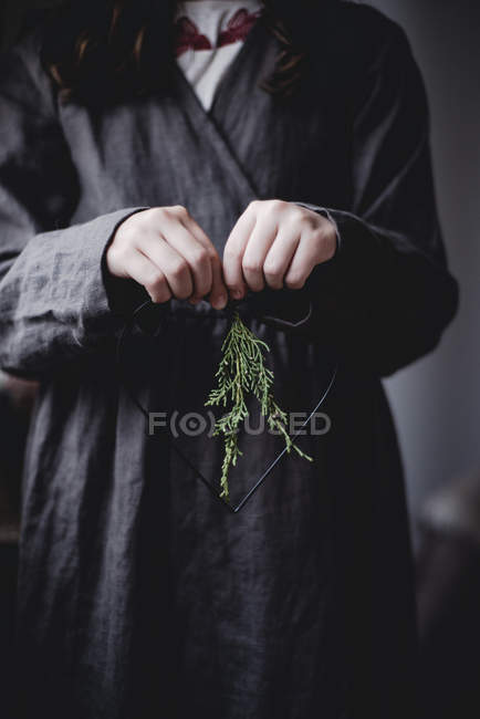 Cropped view of girl holding heart-shaped thuja decoration — Stock Photo