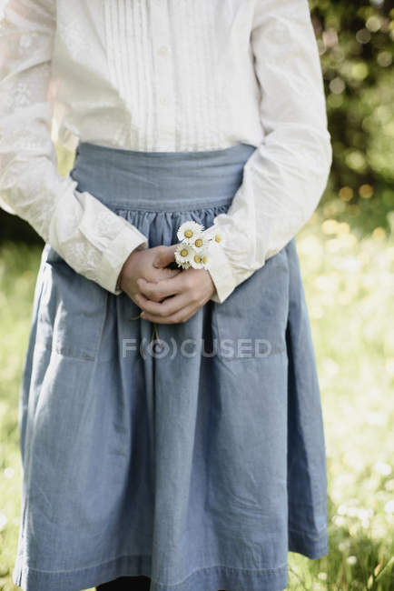 Обрезанный вид девушки-подростка, держащей маргаритки на открытом воздухе — стоковое фото