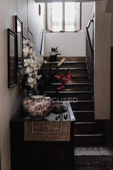 Home interior with lily flowers decoration on bureau by stairs — Stock Photo