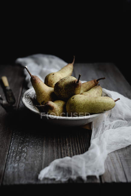 Stillleben mit Birnen in Porzellanschale auf rustikalem Tisch — Stockfoto