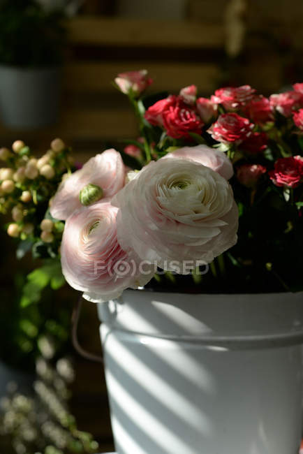Primer plano de los buñuelos rosados en cubo con flores de rosas - foto de stock