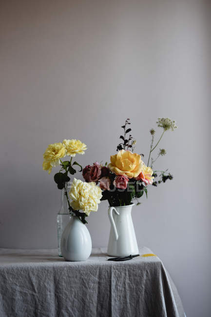 Ramos florales amarillos en jarrones de cerámica en la mesa — Stock Photo