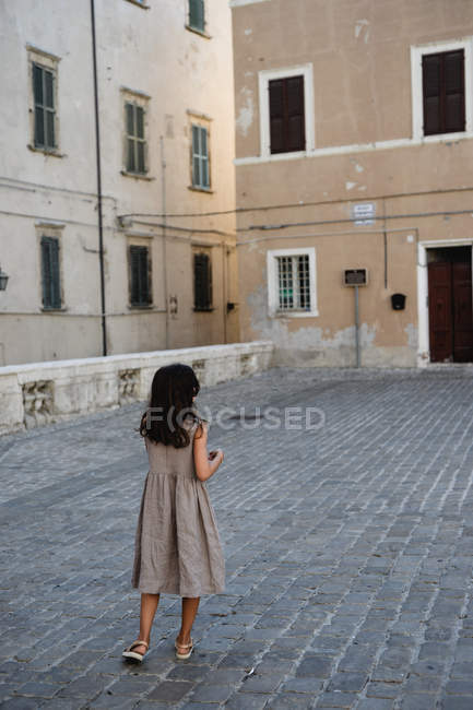 Girl in grey dress walking in old town. — Stock Photo