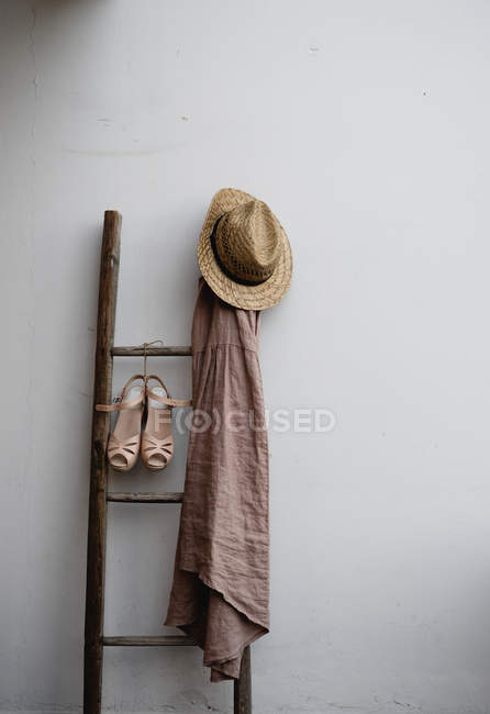 Châle, chapeau de paille et sandales suspendus sur une vieille échelle en bois — Photo de stock