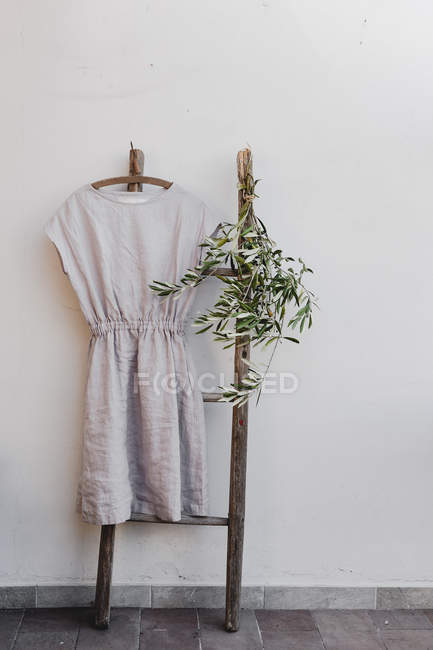 Vestido cinza pendurado na escada velha rústica — Fotografia de Stock