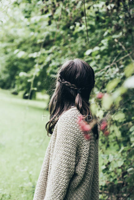 Side view of girl in oversize sweater in countryside garden. — Stock Photo
