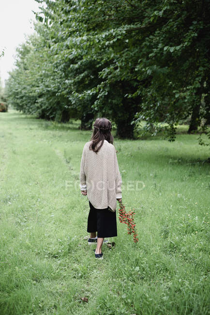 Girl holding branch on red berries in countryside garden. — Stock Photo
