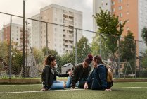 Teenagermädchen nutzen Smartphone und sitzen zusammen auf Tennisplatz — Stockfoto