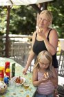 Mother and daughter eating hot dogs in garden — Stock Photo