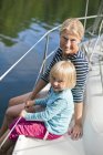 Madre e hija sentadas en la cubierta del barco - foto de stock