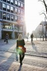 Rückansicht einer Frau, die in Helsinki über die Straße läuft — Stockfoto