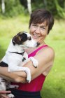 Woman holding dog outdoors, selective focus — Stock Photo