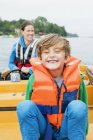 Porträt eines Jungen auf einem Motorboot, Mutter im Hintergrund — Stockfoto