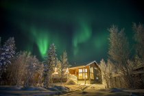 Residental building under aurora borealis illuminated sky — Stock Photo