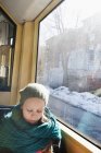 Девушка в вязаной шляпе сидит у окна в трамвае — стоковое фото