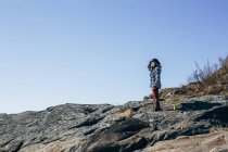 Frau steht am felsigen Strand und blickt in die Ferne — Stockfoto