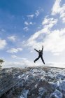 Девушка прыгает через скалу против неба — стоковое фото