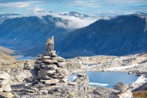 Cairn of stones on top of mountain, with lake and valley view — Stock Photo